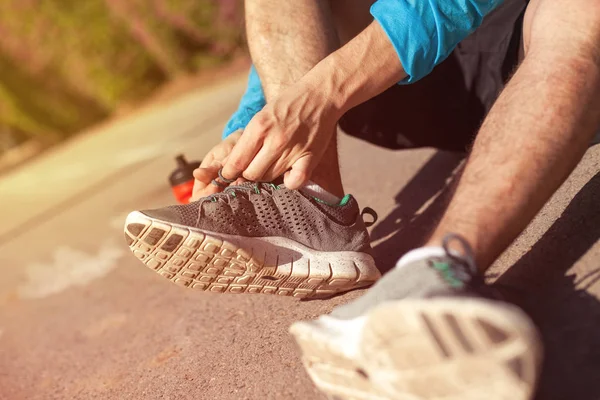 sportsman tie shoelaces on his running shoes in the park