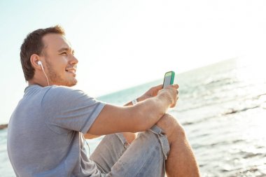 Mobil smartphone ile oturan genç ve gülümseyen adam