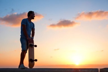man silhouette with skateboard near the ocean clipart