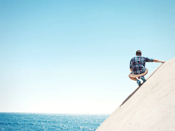 Man sitting on a cliff and sea — Stock Photo, Image