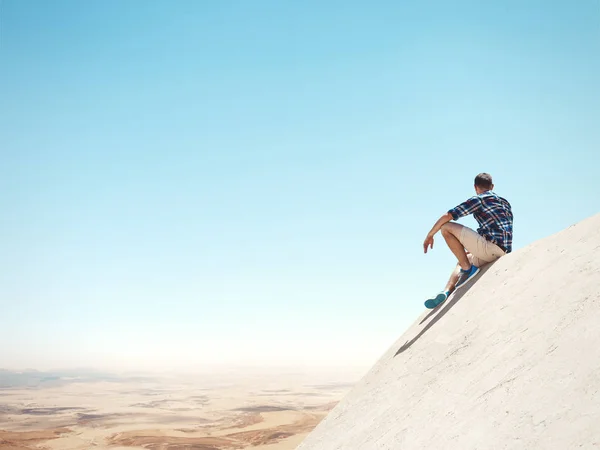 Man sitting on a cliff and desert — Stock Photo, Image