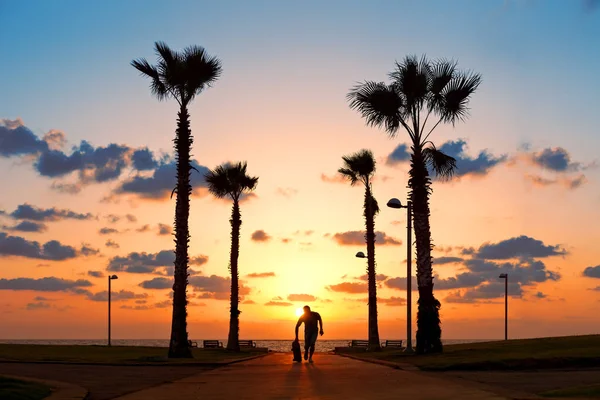 Man running with skateboard in sunset — Stock Photo, Image