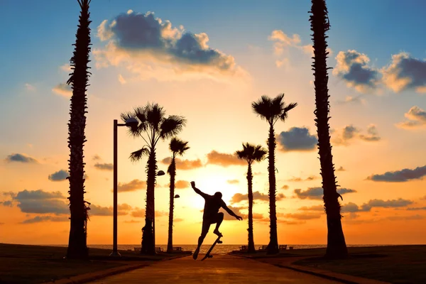 man jumping on skateboard in sunset