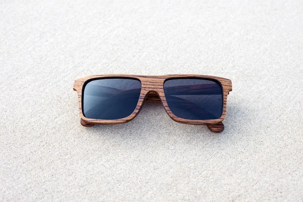 Occhiali da sole in legno sdraiato sulla sabbia — Foto Stock