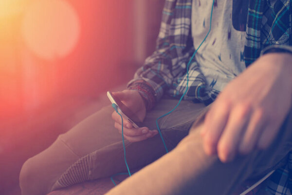 Путешественник держит мобильный телефон с наушниками, сидя на крыше
