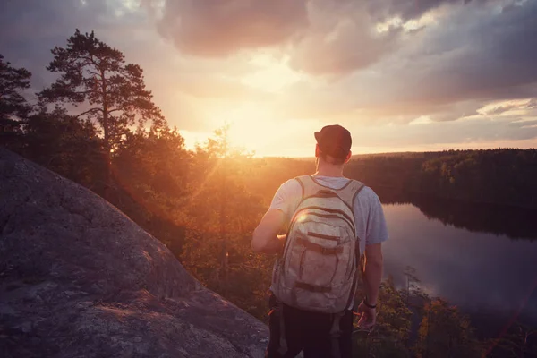 Uomo casuale sulla scogliera sopra il fiume e guardando lontano al tramonto — Foto Stock