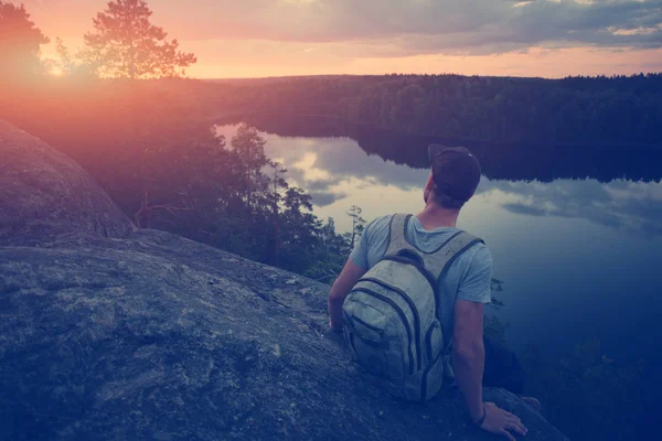 Випадковий чоловік сидить на краю скелі над річкою і дивиться далеко — стокове фото