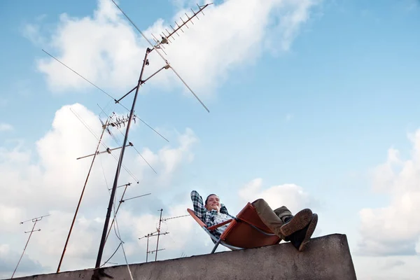 mutlu adam CI çatı kenarındaki sandalyede oturan