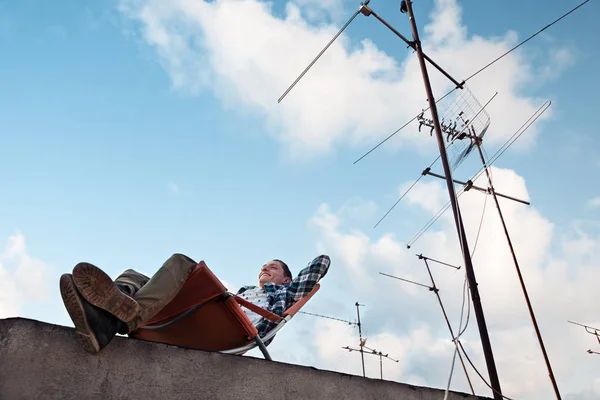 genç adam ben dinlenme çatı kenarındaki sandalyede gülümseyen