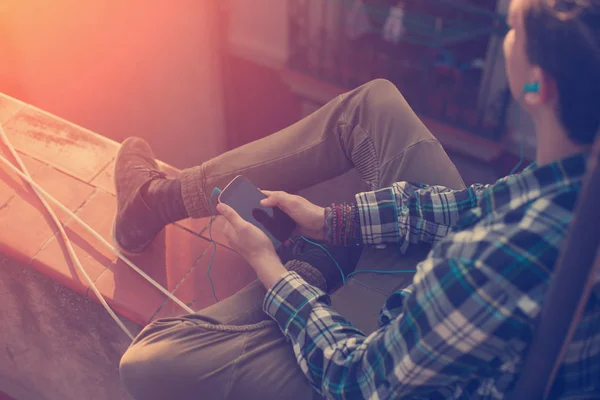 Handsome traveler man sitting on the roof and listening music on