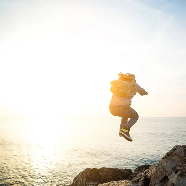 Brave man with backpack jumping over rocks — Stock Photo, Image