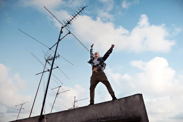 genç adam parlak mavi gökyüzü ve arka plan beyaz bulutlar ile çatı üzerinde atlama