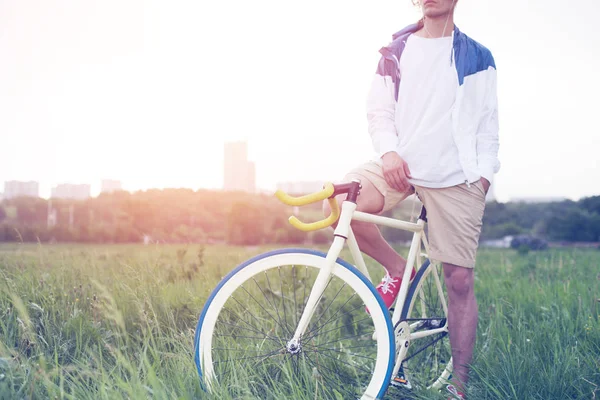 Młody człowiek w puste t-shirt siedząc na rowerze w polu — Zdjęcie stockowe