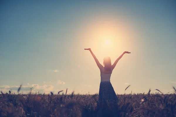 Young girl with outspread hands have fun at sunset in the field — Stock Photo, Image