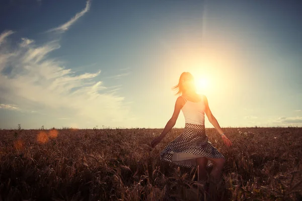 Genç ve yakışıklı kız buğday alanında günbatımında dans 