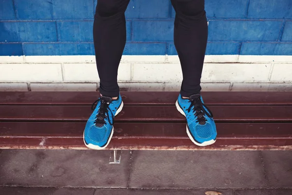 Gros plan des jambes de l'athlète avec des chaussures de course debout sur le banc — Photo