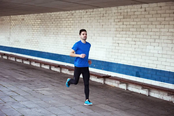 Genç ve yakışıklı atlet açık havada çalışan kulaklıklar ile