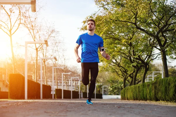 Genç ve yakışıklı erkek atlet parkında çalıştıran