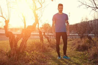 Yakışıklı genç atlet parkında (kasıtlı s gün batımında ayakta