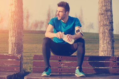 Şişe o ile parkta bankta oturan yakışıklı erkek atlet