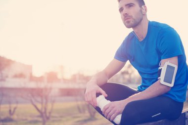 Şişe su ile parkta bankta oturan erkek atlet, 