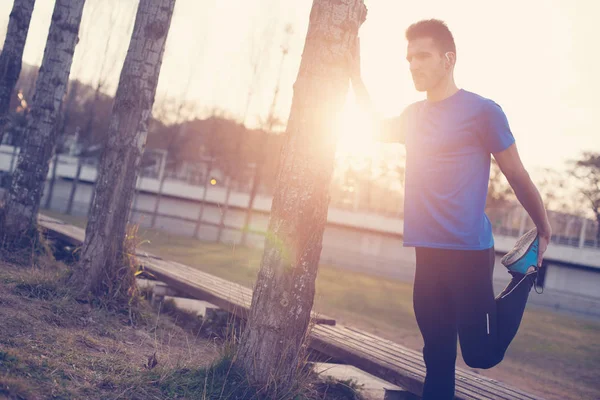Athlète masculin faisant des étirements musculaires pour courir dans le parc à — Photo