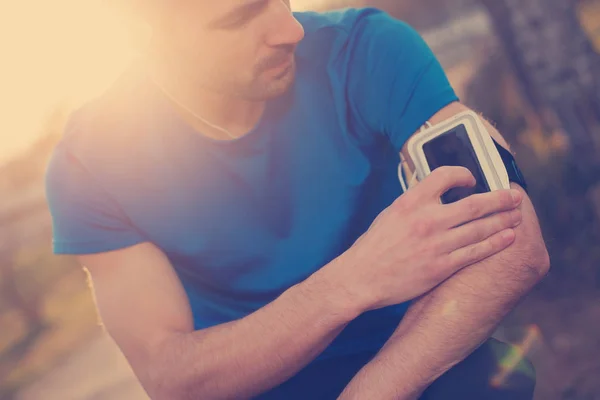 Sportler berührt Handy am Arm (absichtliches Sonnenlicht) Stockbild