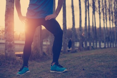 Parkta günbatımında ayakta atlet (kasıtlı güneş parlamayı bir