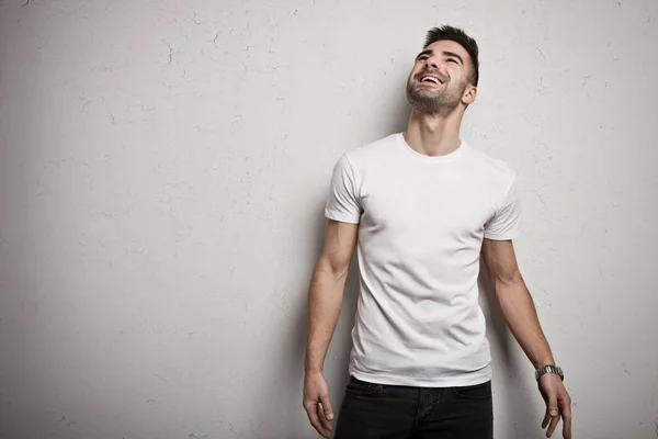 Homme souriant en t-shirt blanc, fond de mur grunge blanc — Photo