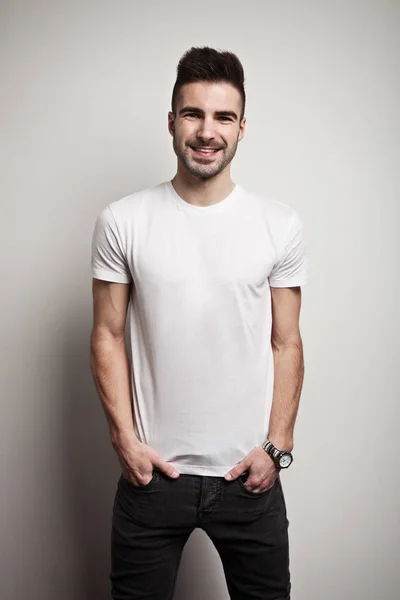 Усміхнений чоловік у порожній футболці, білий фон стіни — стокове фото