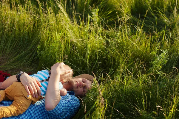Pai feliz deitado na grama com seu filho no peito — Fotografia de Stock