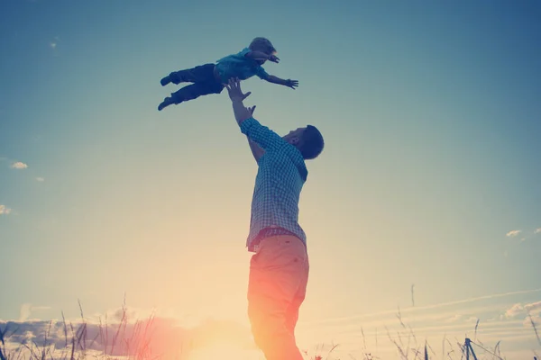 Silhueta de pai brincando com seu filho no parque ao ar livre — Fotografia de Stock