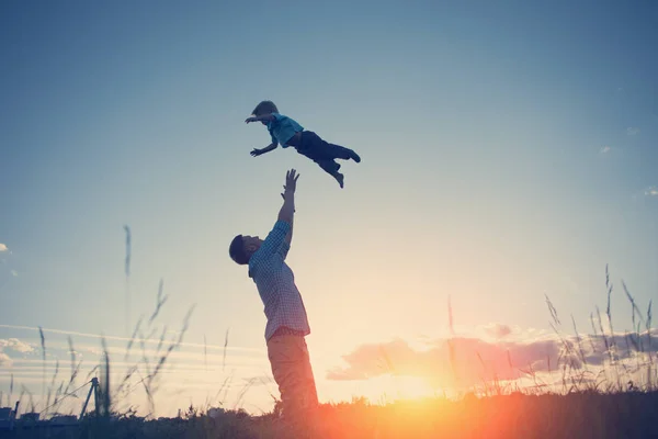 siluet bir baba oğlunu parka kadar günbatımında atma
