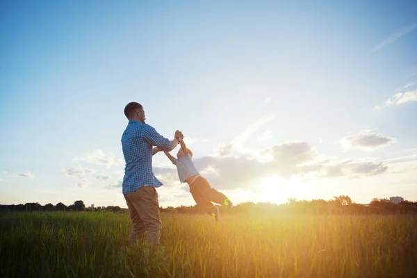 Father spinning with his son in the park at sunset — Stock Photo, Image