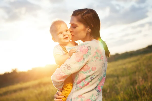 Happy mother kissing her baby in the park — Stock Photo, Image