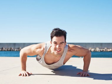 Yakışıklı gülümseyen atlet açık havada yukarı itin yapıyor