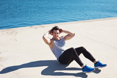 Karın egzersizleri yaparken yakışıklı gülümseyen atlet