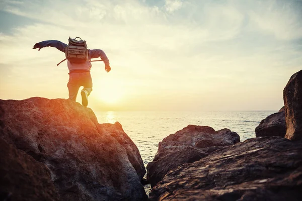 Gezgin ufka günbatımında çalışan deniz kenarında sırt çantası ile