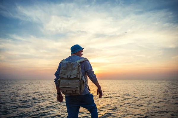 Viaggiatore con zaino vicino al mare guardando lontano all'orizzonte al bellissimo tramonto — Foto Stock