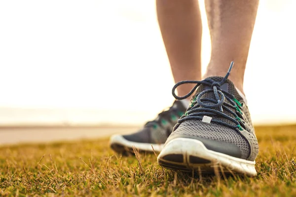 Jambes de sportif debout sur l'herbe en chaussures de course fermer — Photo