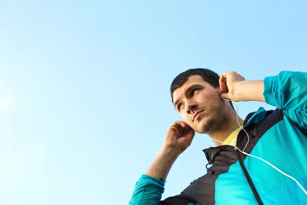 Junger Sportler setzt Kopfhörer mit Musik auf — Stockfoto