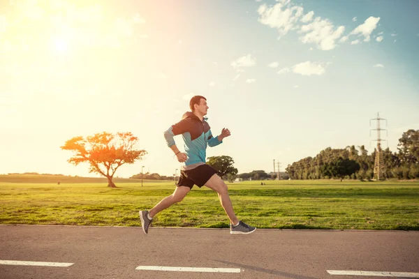 Sportman uitvoeren in het park in de zonsondergang — Stockfoto