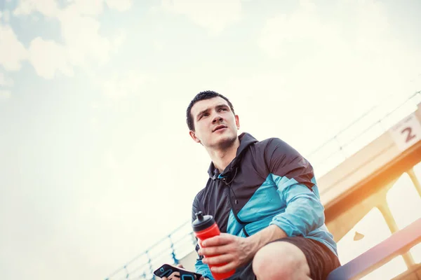 Sportif avec une bouteille d'eau assis à la rampe — Photo