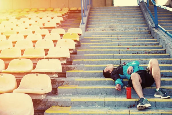 Müder Sportler liegt auf der Treppe und ruht sich im Stadion aus — Stockfoto