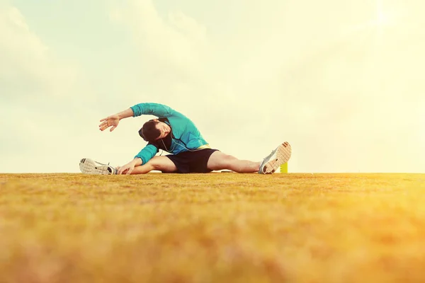 地球温暖化とストレッチ運動公園、太陽フレアと黄色の草を行うスポーツマン ロイヤリティフリーのストック写真
