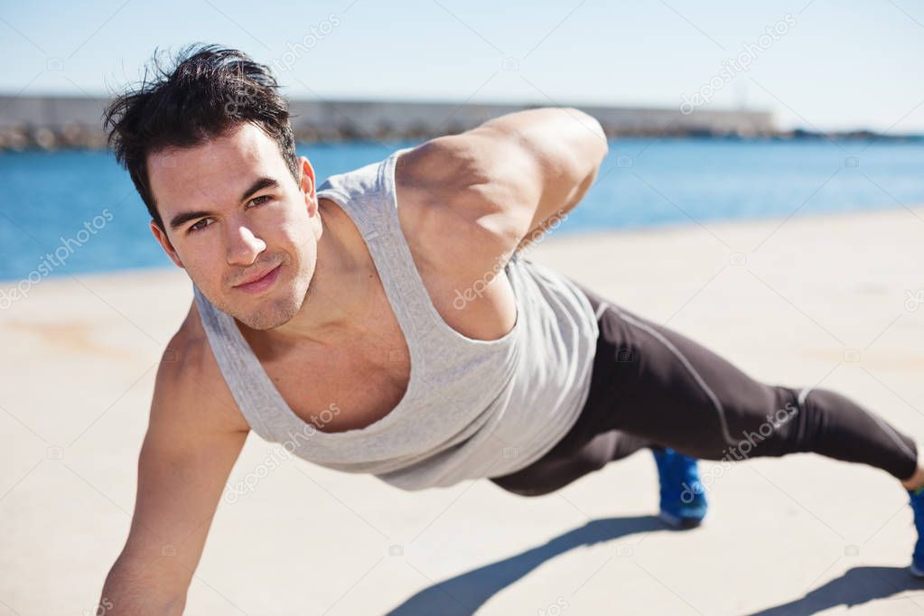 Handsome strong athlete doing one hand push up