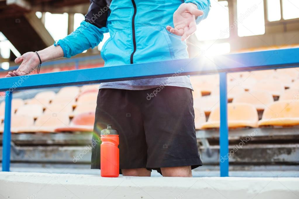 indignant sportsman with bottle of water standing near railing