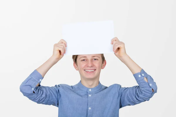 Ένα χαμογελαστό έφηβο αγόρι που κρατάει μια λευκή βίβλο πάνω από το κεφάλι του. Εκπαίδευση — Φωτογραφία Αρχείου