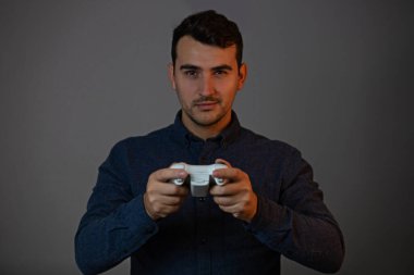 Gri arkaplanda video oyunları oynayan neşeli genç adam