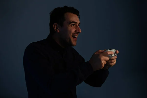 Радостный молодой человек играет в видеоигры изолированные на сером фоне — стоковое фото